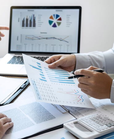 SSZ Beratung kundenspezifische Personalbedarfsermittlung Lösungen Geschäftsanalyse: Zwei Personen diskutieren Diagramme und Daten mit einem Laptop im Hintergrund.